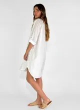 Vestido corto color beige con estampado de formas geométricas en relieve, escote en V y mangas largas.