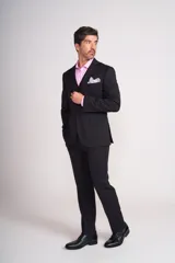 Traje de vestir negro de tres piezas, compuesto por saco, chaleco y pantalón. El saco es de corte clásico con solapa de muesca y dos botones. El chaleco es de cinco botones y el pantalón es de corte recto.