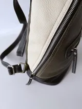 Mochila de cuero verde con detalles en blanco y negro.