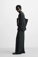 Pantalón negro de corte amplio con cintura elástica ajustable con cordón, bolsillos delanteros y detalle de bolsillo trasero de vivo.