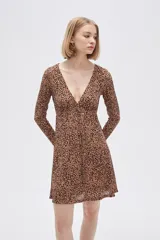 Vestido corto color beige con estampado animal print, escote en V, mangas largas y falda evasé con volados. Ajuste con lazo en la cintura.