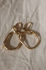 Aros colgantes dorados con forma irregular y textura martillada.