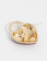 Pin prendedor con forma de corazón cubierto de glitter rojo y aro dorado.