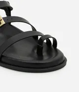 Sandalias negras con tiras de cuero sintético, suela plana y hebillas doradas.