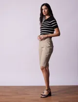 Bermuda color beige a la rodilla, de gabardina elastizada, con pretina ancha elastizada, bolsillos simulados en la parte delantera y bolsillos aplicados en la parte trasera.
