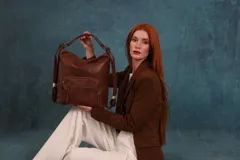 Cartera mochila color tostado, símil cuero, con compartimiento principal amplio y bolsillos frontales con cierre. Tiene correas ajustables para usar como mochila y asa superior para llevar al hombro.