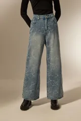 Pantalón de jean azul claro con estampado abstracto desgastado, corte baggy y tiro medio.