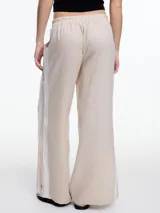 Pantalón de lino negro con elástico en la cintura, tiro medio y calce relajado. Lleva tiras en color gris aplicadas a los laterales, que quedan sueltas en la parte inferior y pueden anudarse.