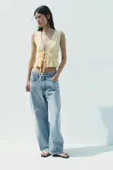 Top amarillo con estampado de cuadros vichy blancos, escote en pico, sin mangas, con detalle de elásticos en la cintura y cierre frontal con lazadas.
