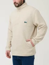 Buzo color beige con cuello alto y cierre de snaps. Diseño de rombos y parche con logo de la marca en el pecho.