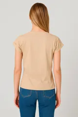 Remera verde militar de corte clásico, con mangas cortas con dobladillo y estampado frontal con diseño abstracto en dorado y texto en inglés.