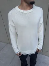 Sweater de hilo blanco roto, de corte holgado, con cuello redondo y mangas largas. Presenta detalles rotos en cuello, puños y ruedo.