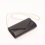 Sobre de vestir negro con textura símil madera y solapa en punta. Incluye cadena dorada desmontable para usar como bandolera.