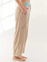 Pantalón largo color beige, tipo baggy, con costuras en verde y etiqueta turquesa en la parte trasera.