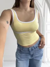 Top amarillo pastel con breteles y borde superior blancos.