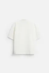 Camisa color blanco con textura de rayas verticales, corte relaxed fit, cuello bowling, manga corta, bolsillo de parche en el pecho y cierre frontal con botones.