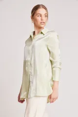 Camisa verde claro de corte recto y mangas largas con puños abotonados. Cierre frontal con botones.