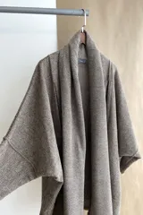 Saco de lana color marrón claro, con mangas amplias, cuello tipo bufanda con flecos y bolsillos laterales. Diseño oversize sin forro.