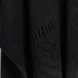 Ruana negra de tejido de punto calado con flecos en el borde inferior.