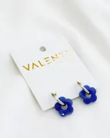 Aros colgantes con aro de acero plateado y dije de acrílico con forma de flor azul.