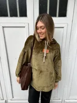 Canguro verde musgo de tela tipo teddy, con capucha y mangas globo. Tiene tajos laterales con tiras ajustables, bolsillo frontal tipo canguro y puños fruncidos.