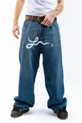 Pantalón de jean azul desgastado, corte mega baggy, con estampa serigrafiada en la pierna y botones personalizados.