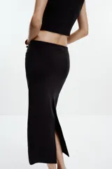 Falda midi color crema, de tiro alto con cintura elástica y detalle de pliegues laterales.