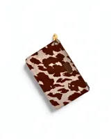 Sobre con cierre de cremallera y correa de mano, con estampado camuflado en tonos marrón, verde y beige.