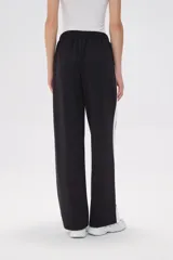 Pantalón de jogging negro con cintura elástica, corte holgado y una franja vertical blanca a lo largo de la pierna.