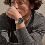 Reloj Skagen Signatur con caja dorada de acero inoxidable y esfera azul con agujas doradas. La correa es de acero inoxidable dorado con eslabones.