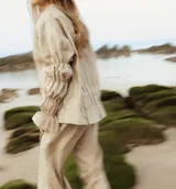 Camisa beige de lino, de corte holgado, con mangas largas abullonadas y puños elásticos.