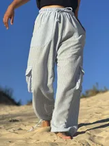 Pantalón de tela rayada celeste y blanco, con cintura elástica y cordón ajustable. Tiene bolsillos laterales y bolsillos tipo cargo en los muslos.
