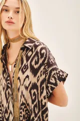 Camisa de corte amplio con estampado ikat en tonos beige y marrón. Tiene cuello camisero, manga corta y botones ocultos.