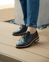 Zapato acordonado color bronce de cuero vacuno con perforaciones decorativas, taco de madera con folia en cuero de 4cm y entre suela de goma de 1,5cm. Horma de punta redonda y cómoda.