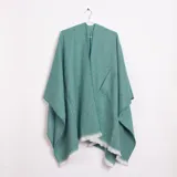 Ruana color verde agua con textura de espiga, cuello en V, un bolsillo frontal y flecos blancos en el borde inferior.