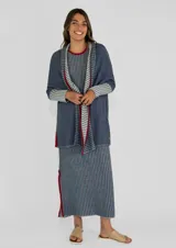 Saco azul de tejido de punto con rayas horizontales en tonos grises y detalles en rojo. Tiene corte holgado, mangas 3/4 y bolsillos laterales.