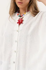 Camisa blanca con calados, escote en V, abotonada y manga 3/4.