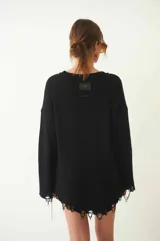 Sweater tejido color crudo, de manga larga con efecto desgastado y deshilachado en el ruedo y puños. Tiene cuello redondo y calce holgado.