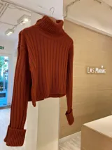 Sweater de punto color verde oliva, con cuello alto y mangas largas con puños acanalados.