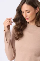 Buzo tejido de lana color beige, con cuello alto, calce cómodo y diseño minimalista. Presenta puños y ruedo acanalados.