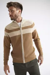Campera tejida de algodón a rayas horizontales en tonos azul marino y azul. Tiene cuello alto, cierre frontal completo, mangas largas y logo metálico en la parte inferior.