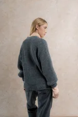 Saco de lana color verde oliva, con silueta oversize, mangas balloon, punto perlado y cuello en V.