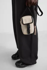 Bandolera vertical negra de acabado engomado con compartimento principal con cierre de cremallera y bolsillo interior plano. Bolsillo frontal con cierre de hebilla de liberación rápida. Asa de hombro ajustable y extraíble.