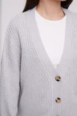 Cardigan de tejido holgado color crudo, con botones y mangas largas.