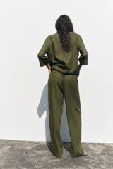 Pantalón color beige de lino, de tiro alto con cintura elástica, bolsillos laterales ocultos en costura y pernera ancha.
