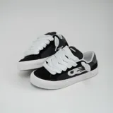 Zapatillas bajas de gamuza negra con detalles en cuero sintético blanco y suela de goma blanca.
