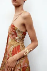 Brazalete rígido dorado con forma de serpiente enroscada.