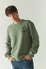 Buzo de felpa color gris claro con cuello redondo y puños y cintura acanalados. Estampado en la espalda con motivos de la naturaleza en tonos azul, verde y negro.