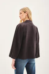 Saco de lino color negro, de corte amplio, con solapa, bolsillos falsos y pin de guitarra en la solapa.