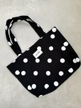 Bolso tipo tote bag de lona color crudo con estampado de lunares negros. Posee dos asas de hombro y una etiqueta blanca con el logo "AIRE" en el centro.